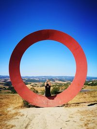 Reflection of young woman in water against clear blue sky