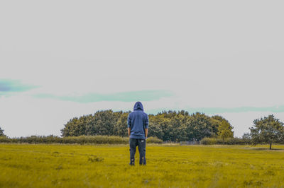 Rear view of man standing on field against sky