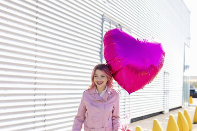 Portrait of woman standing against pink wall