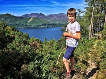 Full length portrait of boy standing by derwent water and mountains against sky