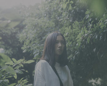 Thoughtful young woman standing by leaves