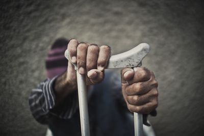 Man holding crutch against wall
