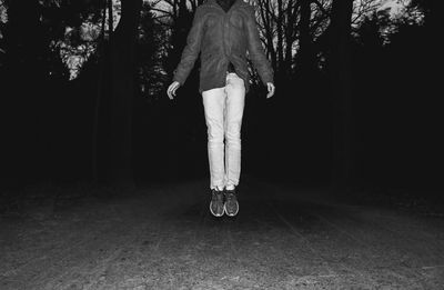 Low section of man on tree trunk at night