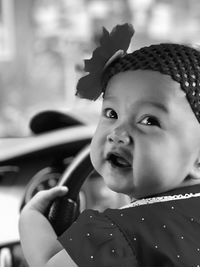 Close-up of cute baby girl holding steering wheel in car