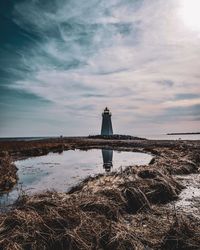 Lighthouse by sea against sky