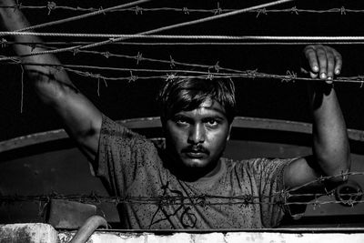 Man standing by barbed wire fence