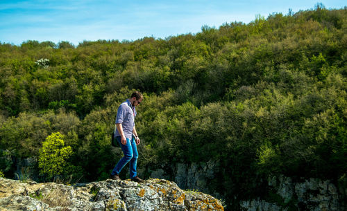 Hiker standing on rock formation against trees