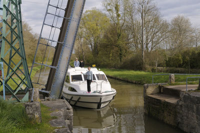 Boat in canal amidst trees against sky