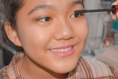 Portrait of a young girl getting make-up applied to her face 