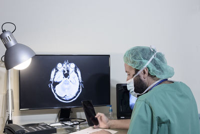 Doctor with smart phone sitting at table