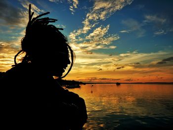 Silhouette woman looking at sea against sky during sunset