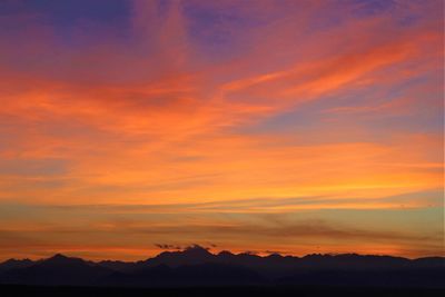 Scenic view of silhouette mountains against orange sky