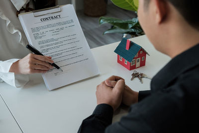 Midsection of estate agent explaining contract to client at office