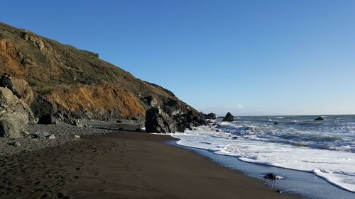 Scenic view of beach against clear blue sky