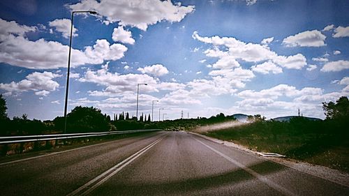 Country road against cloudy sky