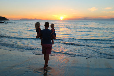 Woman standing on beach against sky during sunset