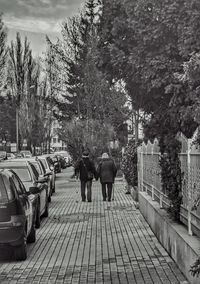 Rear view of people walking on footpath in city