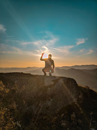 Man standing on shore against sky during sunset