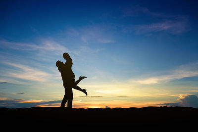 Silhouette man standing on field against sky during sunset