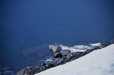 Scenic view of sea by snowcapped mountain against sky