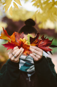 Close-up of woman holding maple leaf during autumn