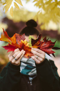 Close-up of hand holding maple leaf during autumn