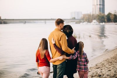 Rear view of friends on shore against sea