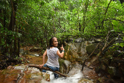 Young woman sitting in front of waterfall in forest