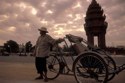 Rear view of man standing against sky at sunset