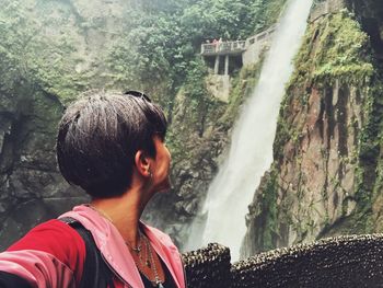 Woman looking at waterfall while standing by railing