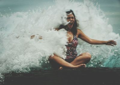 Full length of woman enjoying in wave on shore at beach