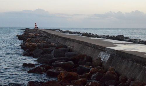 Pier on sea against cloudy sky