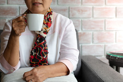 Old woman hold a cup of hot coffee drink at home