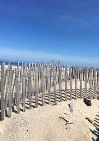 Row of chairs on sand at beach against clear sky