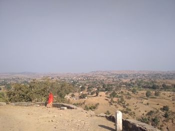 Rear view of woman standing on landscape against clear sky