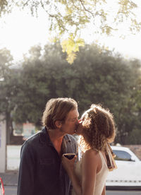 Couple kissing on street during sunny day