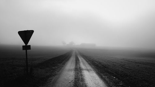 Road sign on street against sky