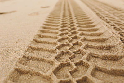 Close-up of tire tracks at sandy beach