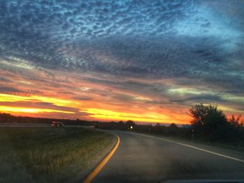 Road passing through landscape against cloudy sky