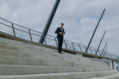 Businessman walking on staircase against sky