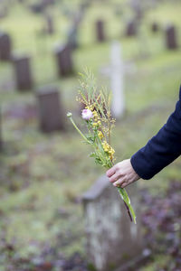 Womans hand holding flowers on cemetery, skogskyrkogarden, stockholm, sweden