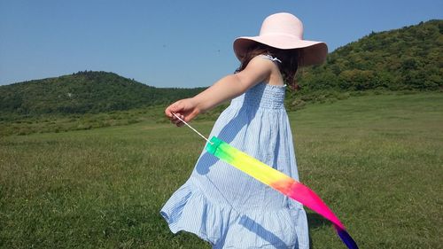 Woman holding umbrella while standing on field against sky