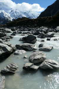 Rocks on snowcapped mountains against sky