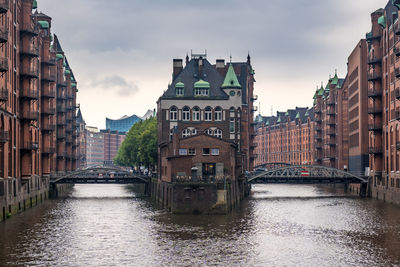 Canal amidst buildings in city against sky