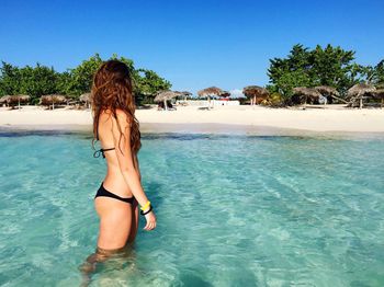 Side view of woman in bikini standing in sea