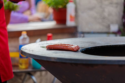 Two sausages are warmed up on a round stove in a street cafe