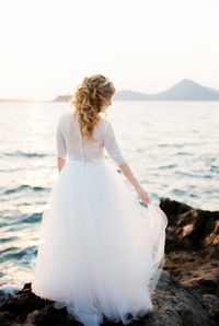 Rear view of woman standing at beach