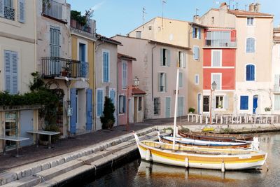 Boats moored in canal by buildings in city