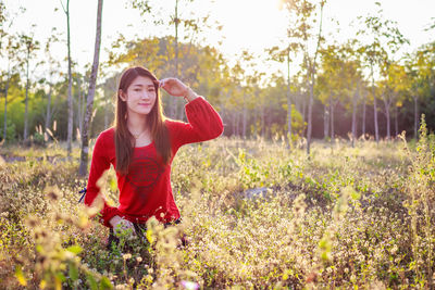 Portrait of young woman standing against plants