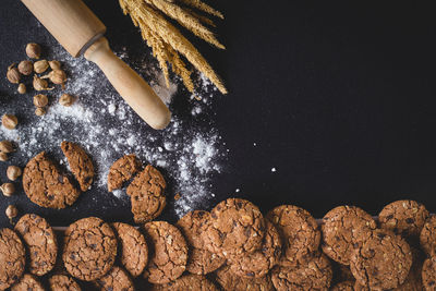 Directly above shot of chocolate chip cookies and rolling pin on black background